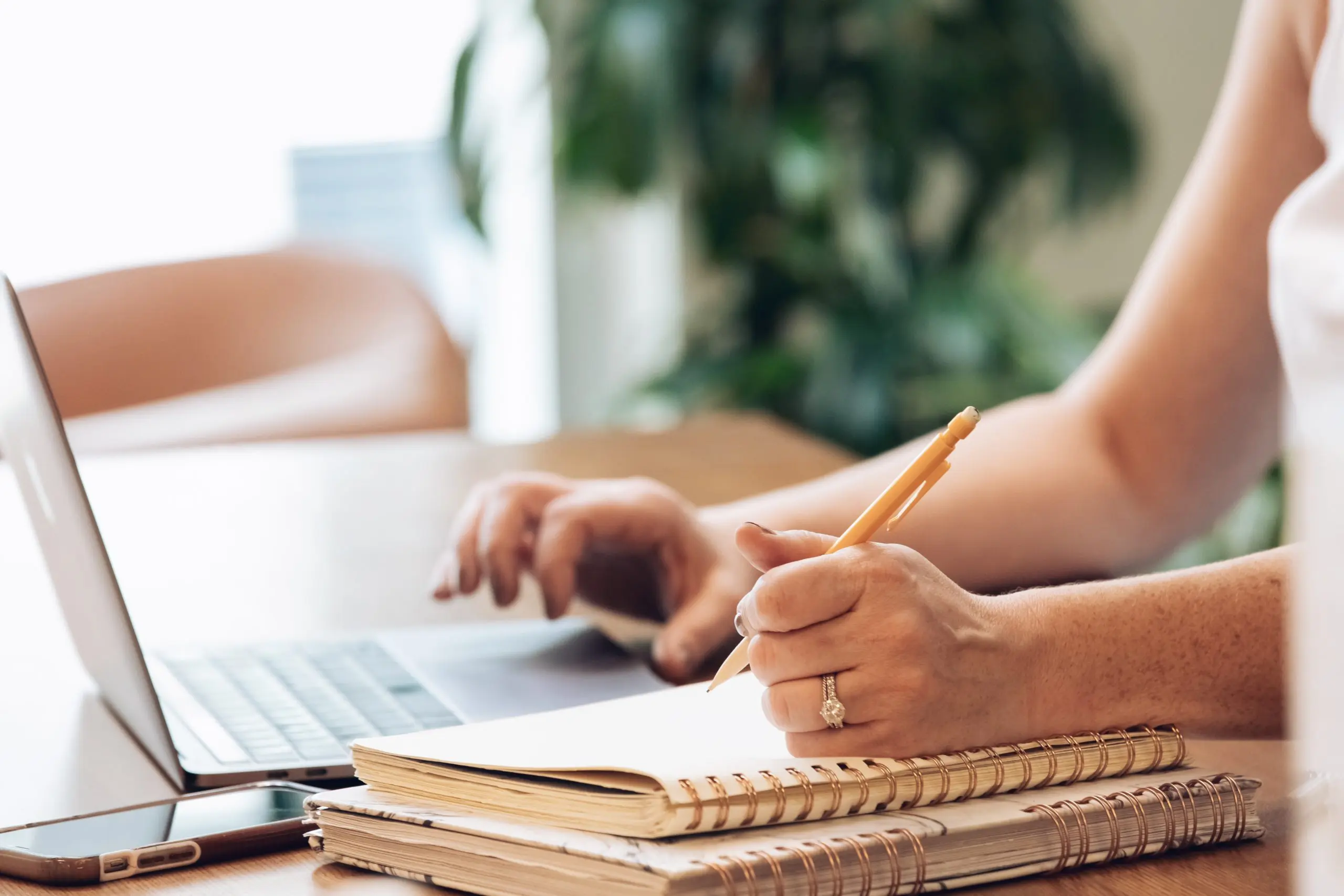 professional copywriter using notepad and laptop to come up with words that will get a customers attention